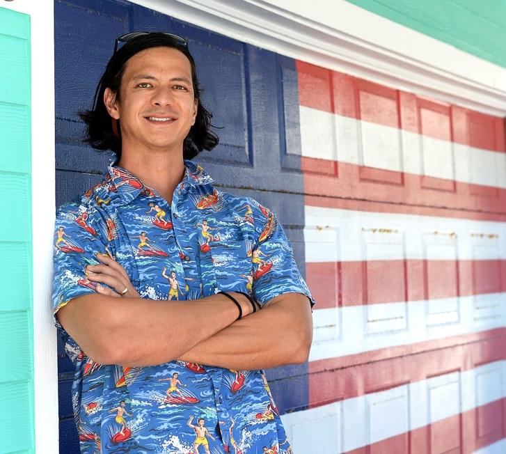 Matthew Chang, arms crossed, in front of a garage door painted as an American flag
