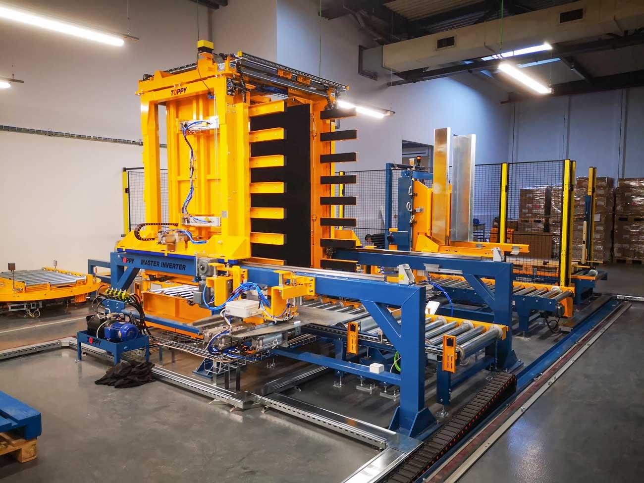 Yellow and blue pallet-changing machinery on a factory floor