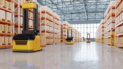 Yellow automated guided forklifts moving between pallet racks in a warehouse
