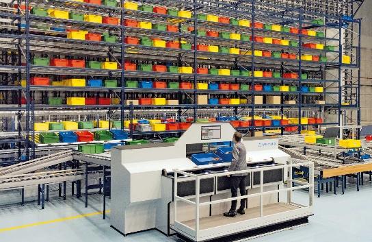 Operator at a goods-to-person picking station in front of tote storage racks