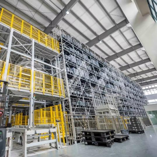 Tall automated storage racks with yellow material-handling equipment